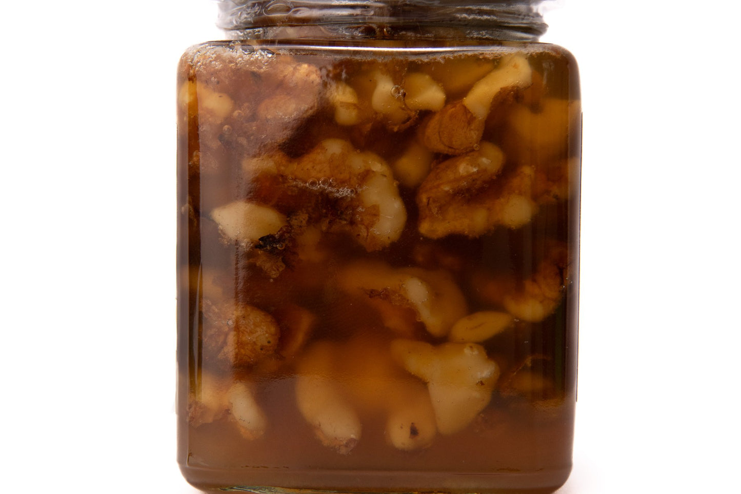 Close-up of walnut pieces in golden raw honey spread